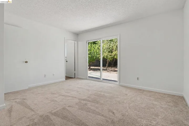 Spacious room featuring neutral carpeting and white walls, with a sliding glass door providing outdoor access