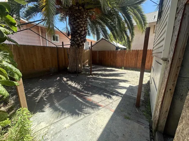 Private outdoor space featuring a mature palm tree, paver patio, wood fencing, and concrete pathways