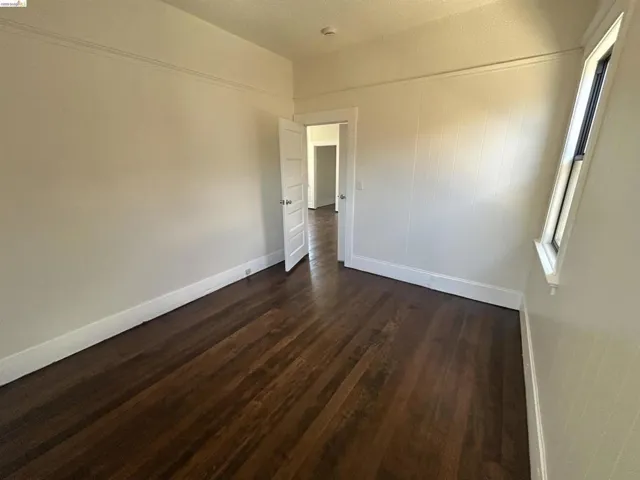 Room featuring dark wood-finish flooring, white baseboards, and light-toned walls