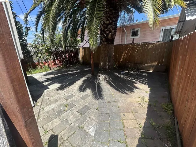 Paved patio area featuring a mature palm tree providing natural shade