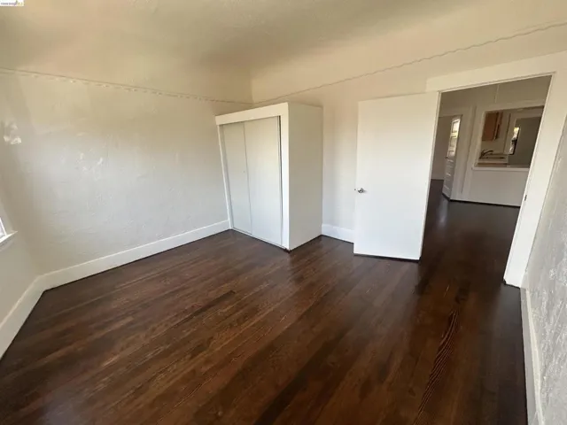 Hardwood flooring and white baseboards define this room, featuring a built-in closet with sliding doors and a white painted door
