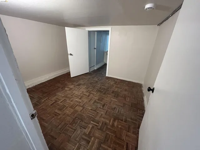 Room featuring parquet wood-finish flooring, white painted walls, and a white interior door