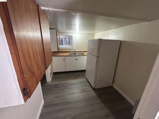 Kitchen featuring wood-finish upper cabinetry, white lower cabinetry, and a double basin sink