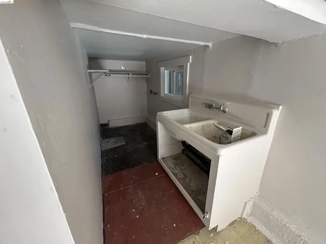 Utility room featuring a double basin sink with wall-mounted faucet, a single window, and a built-in shelf with hanging rod