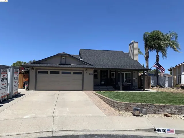 Single-story residence featuring a two-car garage with a concrete driveway and brick-edged planter