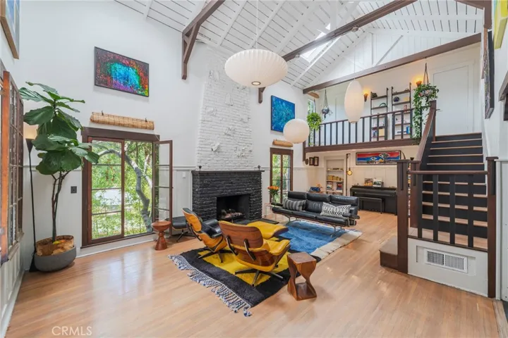 Dramatic living room featuring soaring ceilings, original architectural character, and a striking fireplace that anchors the home's historic charm.