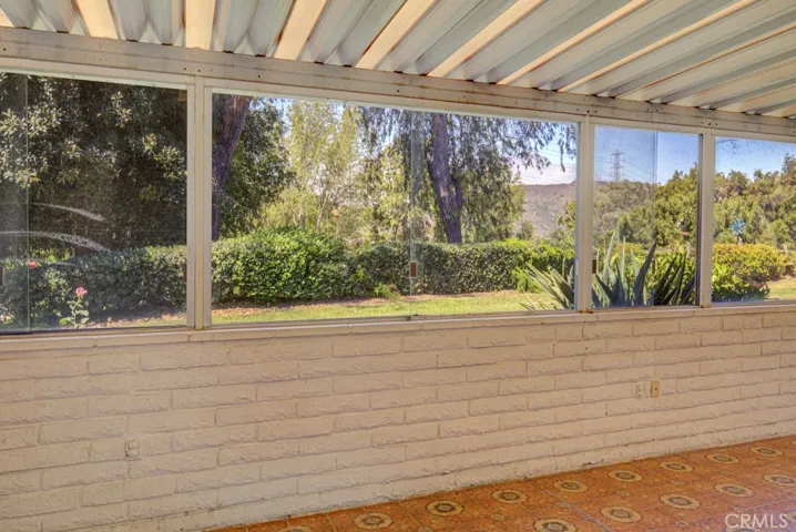 Another view of the covered rear patio. There is a lovely view of an attractive greenbelt and the trees and hills beyond.