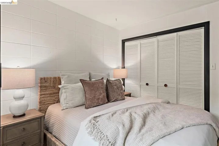 Bedroom featuring a textured accent wall, built-in bi-fold louvered closet doors with dark trim, and recessed lighting