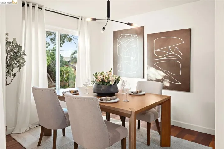 Dining area featuring a contemporary chandelier, wood-finish flooring, and a large window with white drapery