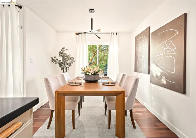 Dining area featuring wood-finish flooring, white walls, and a modern chandelier