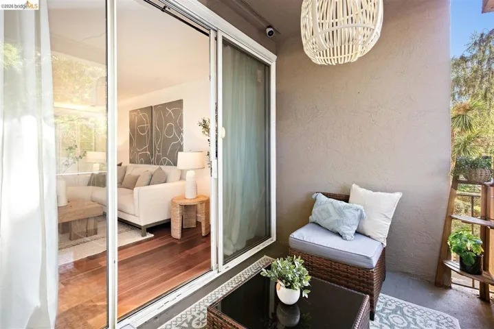 Private outdoor balcony featuring a woven light fixture and a textured wall finish