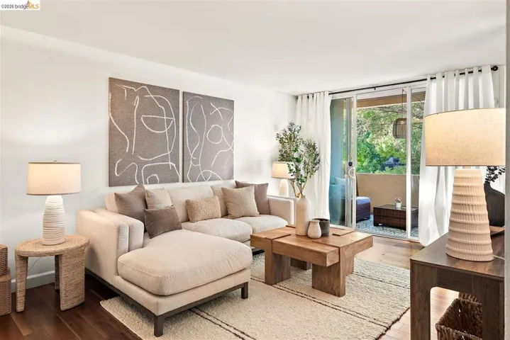 Living room featuring wood-finish flooring, white walls, and a sliding glass door opening to a private balcony