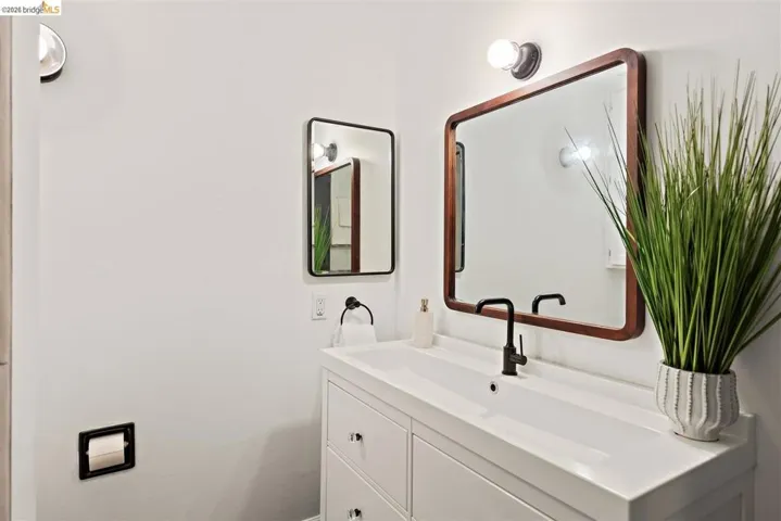 Bathroom vanity featuring a white integrated sink, dark bronze faucet, and a large wood-framed mirror