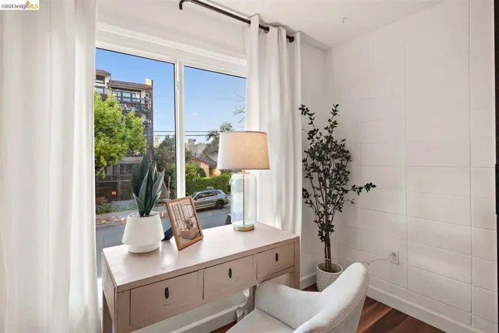 Room featuring a large window, white walls with textured paneling, and wood-finish flooring