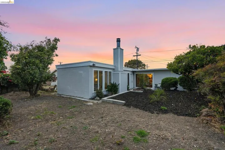 Single-story residence featuring a contemporary grey exterior, a prominent chimney, and multiple large windows