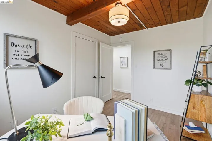 Room featuring a vaulted wood-planked ceiling with exposed beams, white walls, and wood-finish flooring