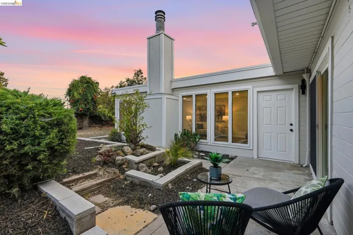 Private patio area featuring a concrete surface, a white paneled door, and multiple windows