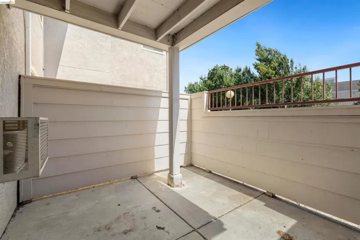 Covered outdoor patio with a concrete floor, horizontal paneling, and a metal railing