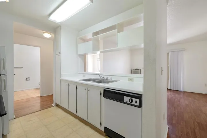 Kitchen featuring white cabinetry, a double basin stainless steel sink, and a built-in dishwasher