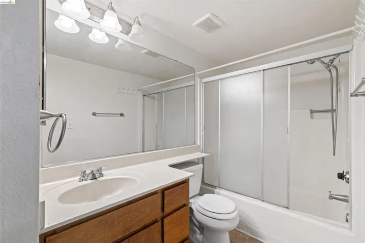 Bathroom featuring an integrated sink with a chrome faucet, wood-finish vanity, and a large wall-mounted mirror
