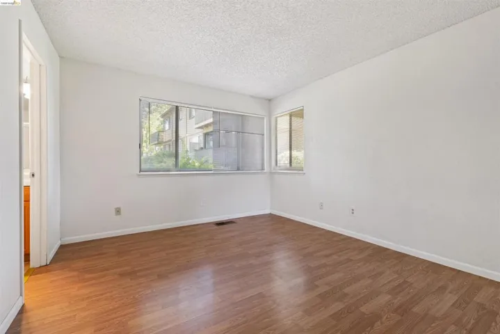 Spacious room featuring wood-finish flooring, white walls, and a textured ceiling