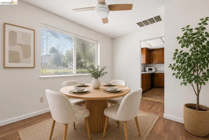 Dining area featuring wood-finish flooring, a contemporary ceiling fan, and a large window with horizontal blinds