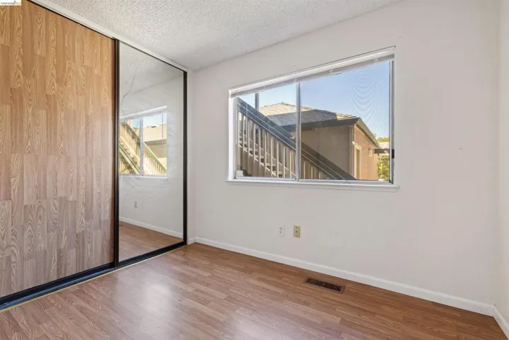 Bedroom featuring wood-finish flooring, a large window, and mirrored closet doors