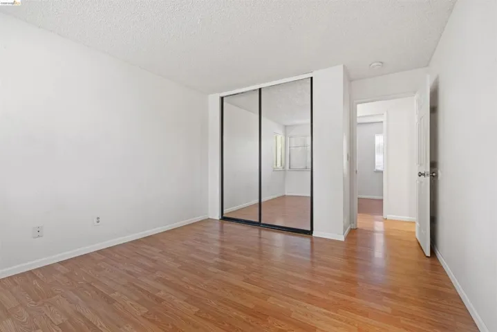 Bedroom featuring wood-finish flooring, white walls, and a ceiling with textured finish
