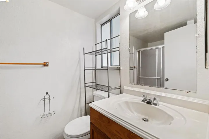 Bathroom featuring a single vanity with wood-finish cabinetry, a white countertop, and a chrome faucet