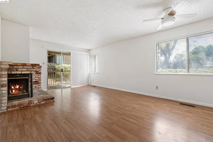 Spacious room featuring wood-finish flooring, a brick fireplace, and a sliding glass door opening to an outdoor area
