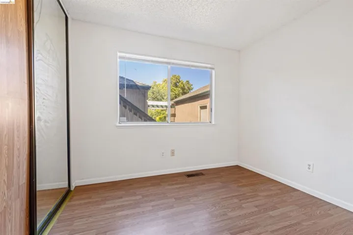 Bedroom featuring wood-finish flooring, white walls, and a window with blinds