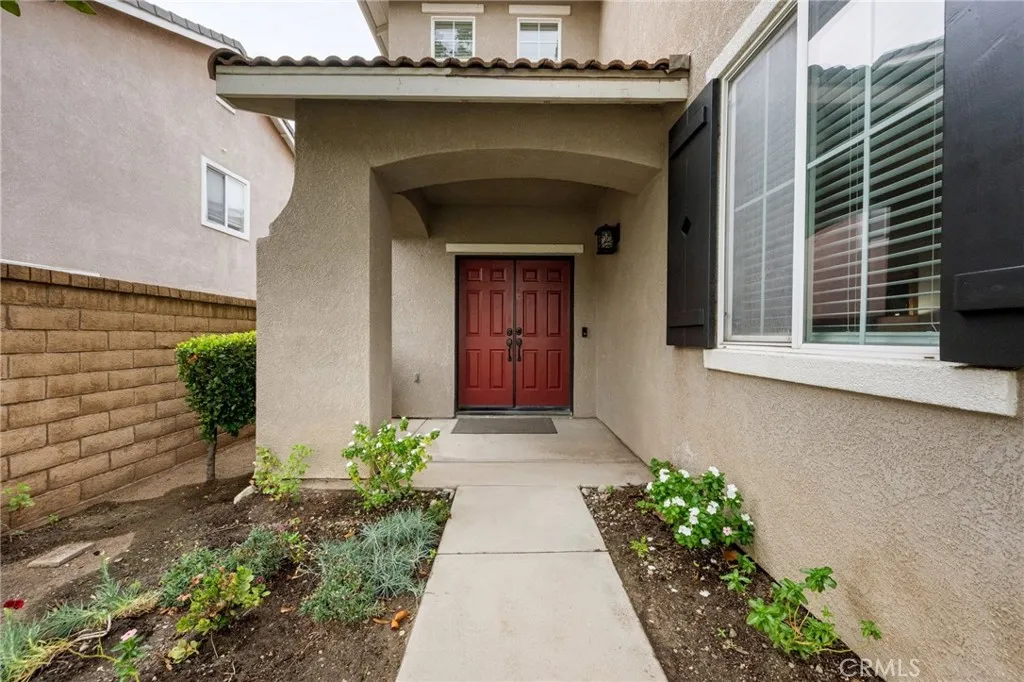 Charming covered entry with dual doors and freshly landscaped walkway.