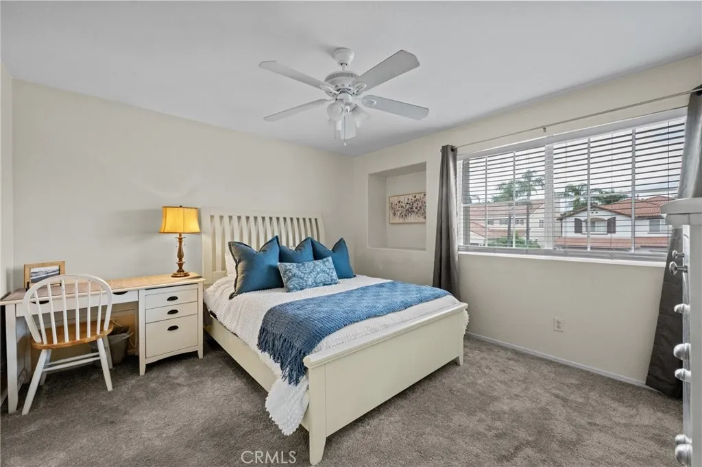 Northeast bedroom featuring a ceiling fan and bright, welcoming natural light with plush carpet. Bedroom has a walk-in closet.