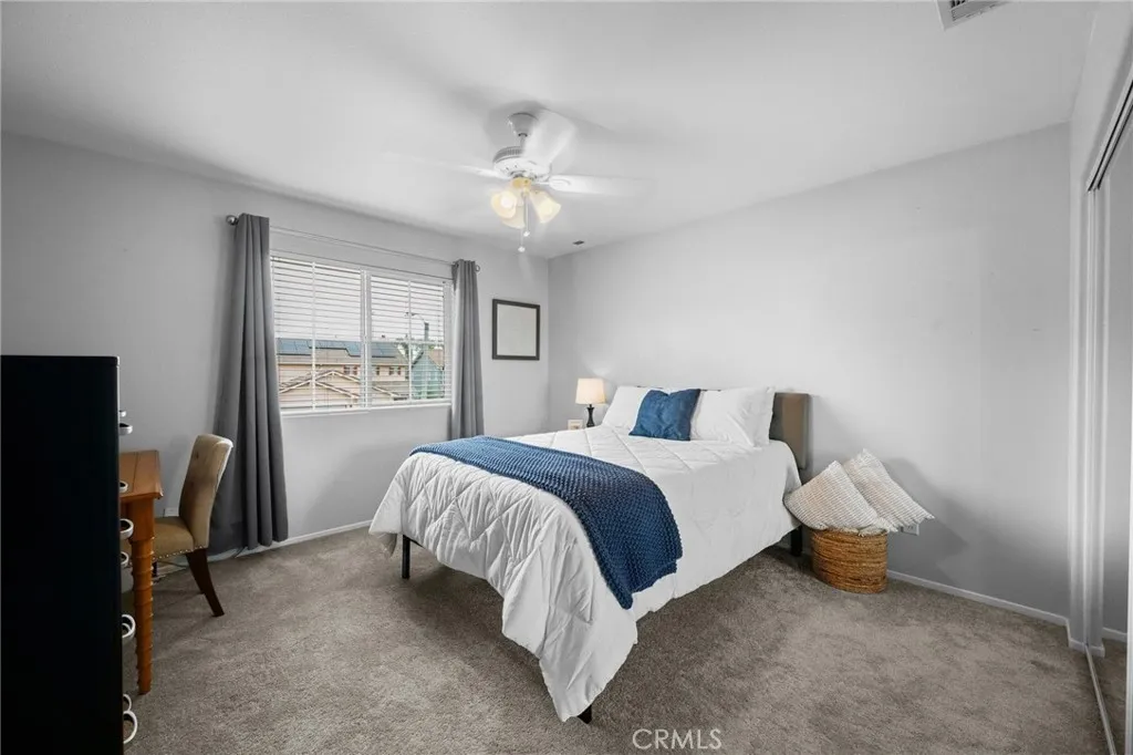 Bright southeast-facing bedroom with plush carpet and a ceiling fan.