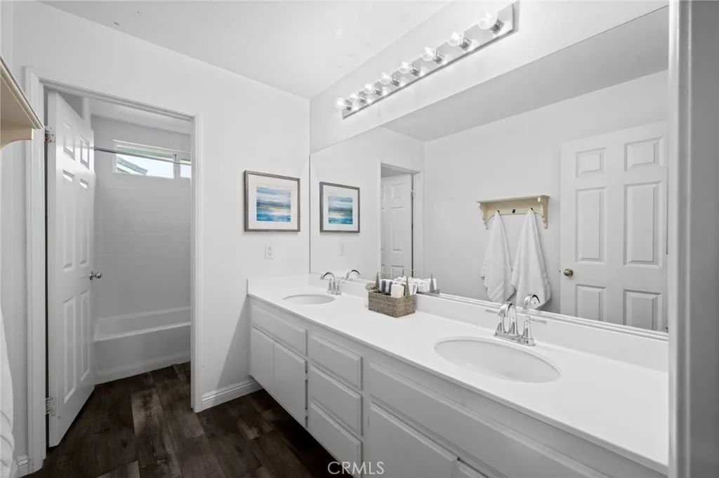 Hall bathroom featuring a dual-sink vanity and vinyl plank flooring.