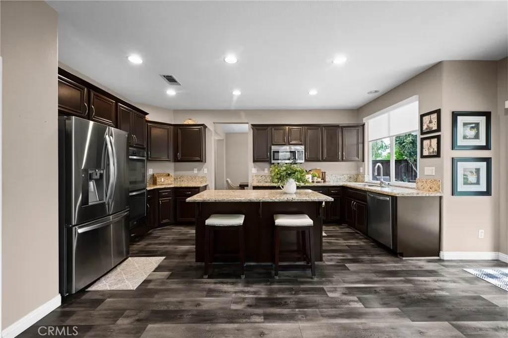 Chef-inspired kitchen featuring espresso cabinetry, granite countertops, stainless steel appliances, and a large center island.