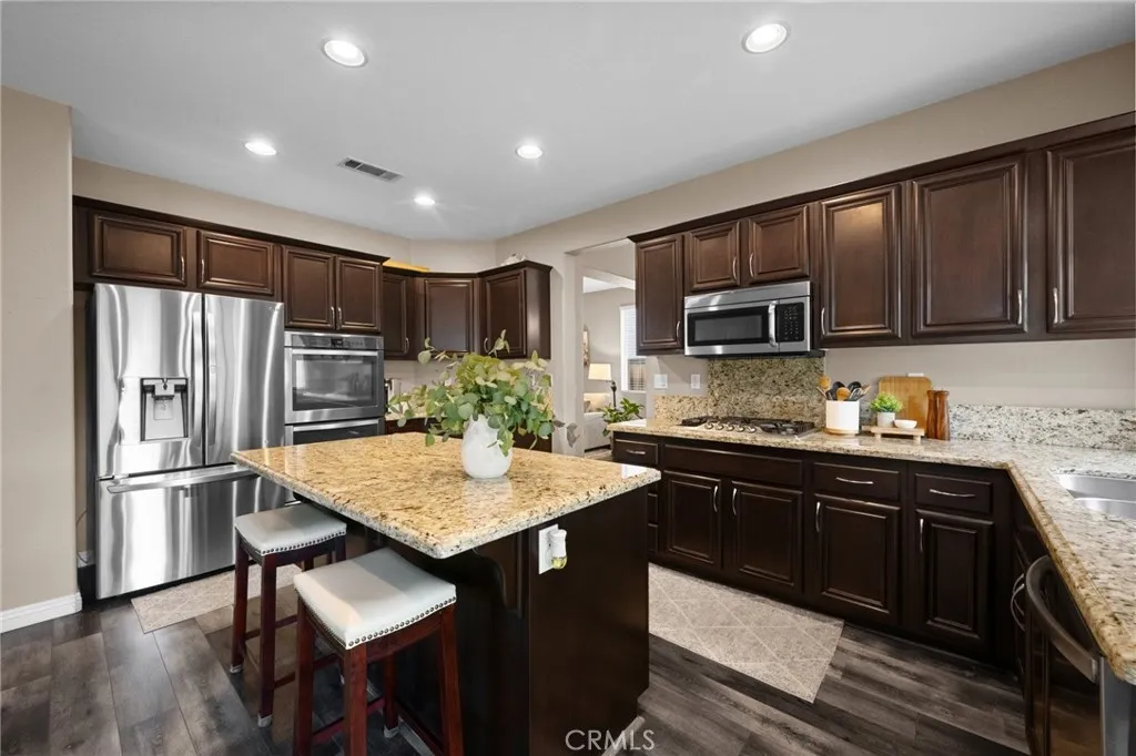 Chef-inspired kitchen featuring espresso cabinetry, granite countertops, stainless steel appliances, and a large center island.
