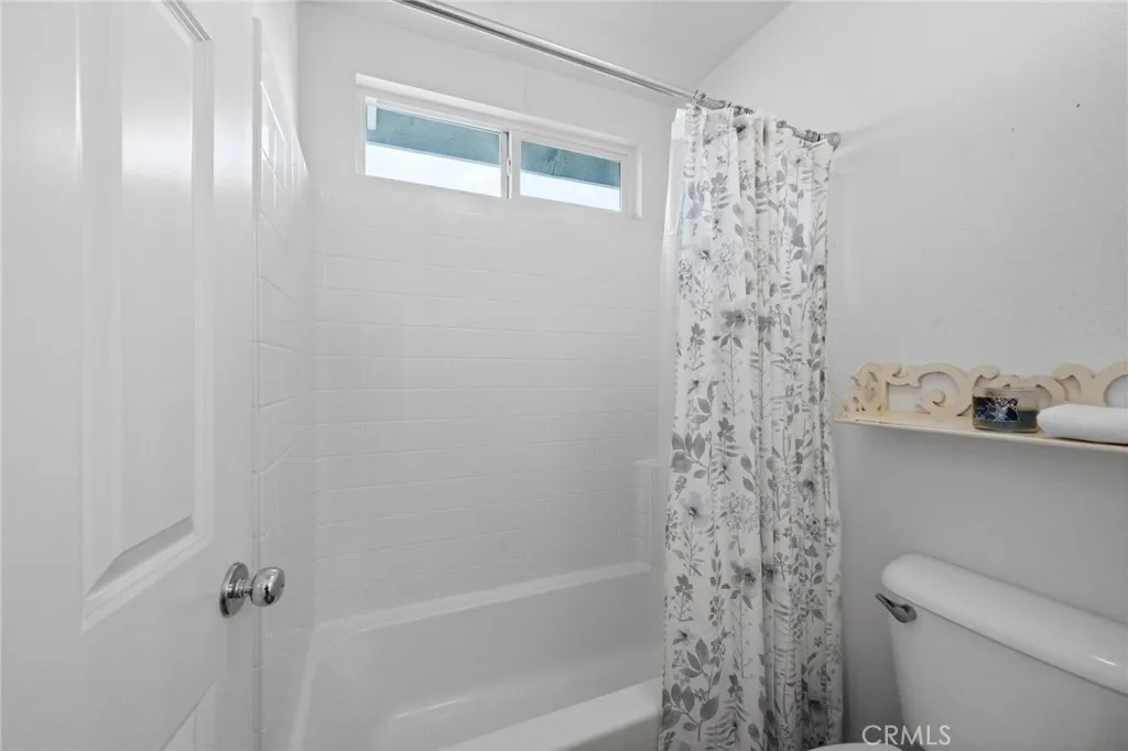 Hall bathroom featuring shower-in-tub combo with a bright window and vinyl plank flooring.