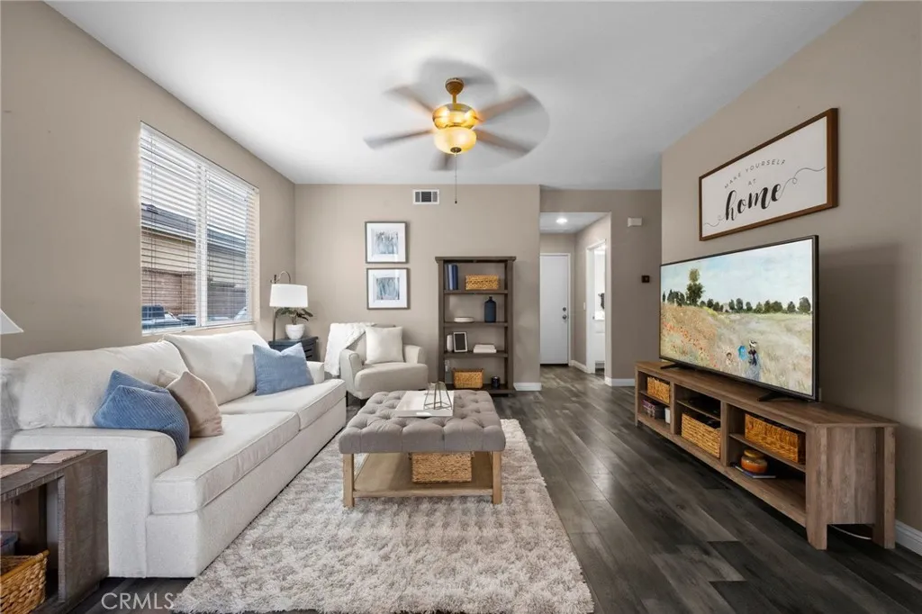 Comfortable part of the Great Room with plush seating, a ceiling fan, and an open view to the kitchen.