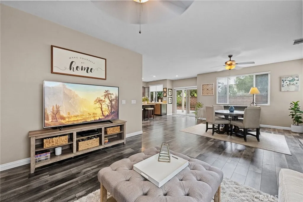 Comfortable part of the Great Room with plush seating, a ceiling fan, and an open view to the kitchen.