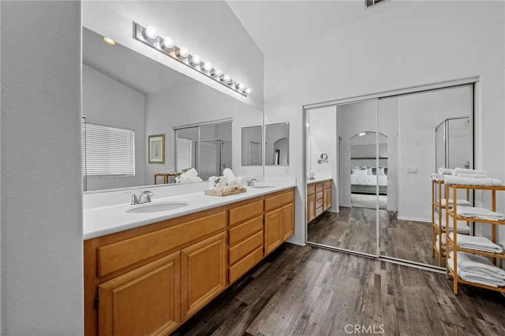 Primary bathroom featuring a dual-sink vanity with dual walk-in closets and private water closet.