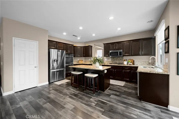 Chef-inspired kitchen featuring espresso cabinetry, granite countertops, stainless steel appliances, a large center island, and large walk-in pantry.