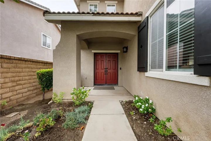 Charming covered entry with dual doors and freshly landscaped walkway.