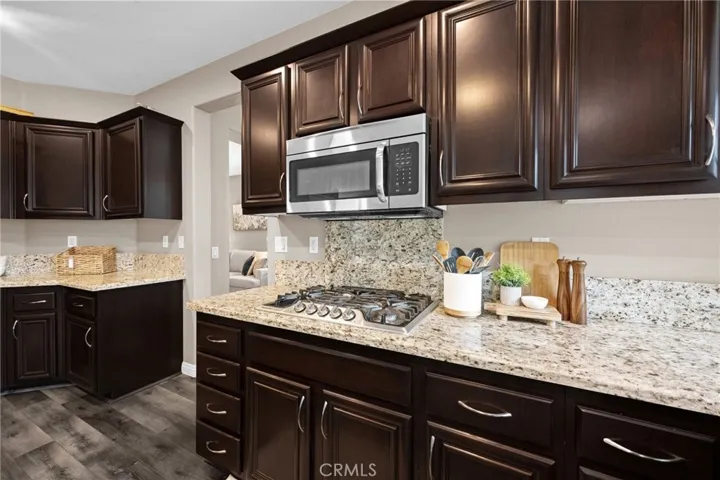 Detailed view of the kitchen's tile backsplash, stainless appliances, and ample cabinet storage.