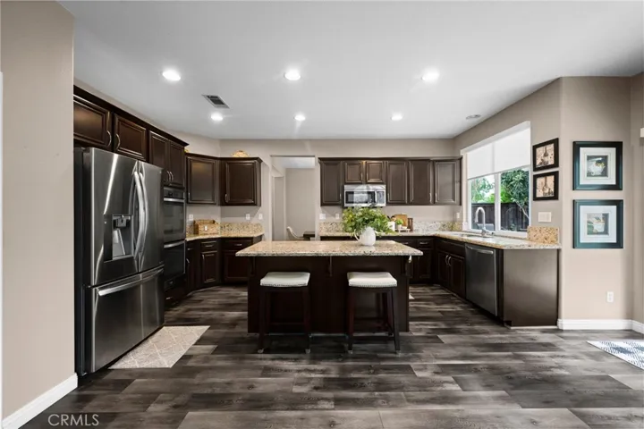 Chef-inspired kitchen featuring espresso cabinetry, granite countertops, stainless steel appliances, and a large center island.