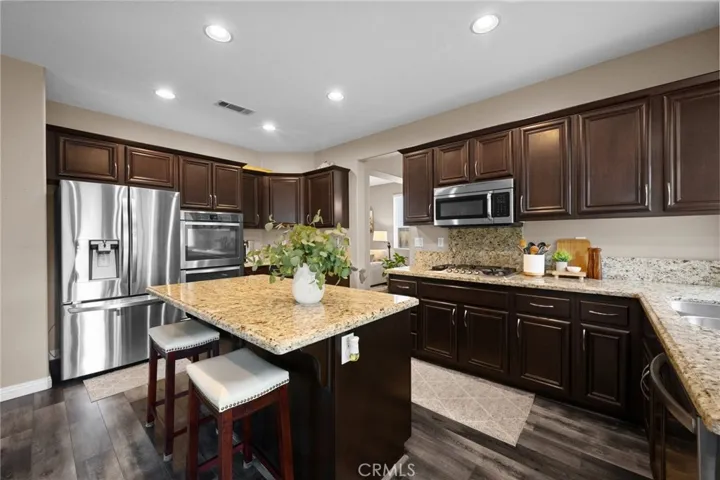 Chef-inspired kitchen featuring espresso cabinetry, granite countertops, stainless steel appliances, and a large center island.