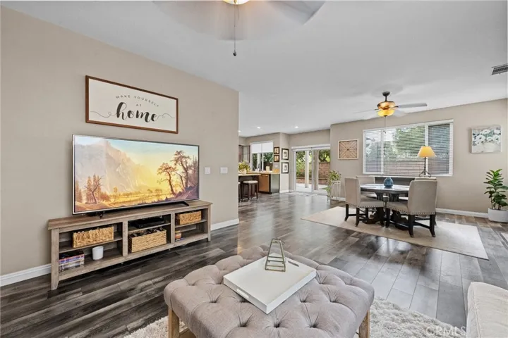 Comfortable part of the Great Room with plush seating, a ceiling fan, and an open view to the kitchen.
