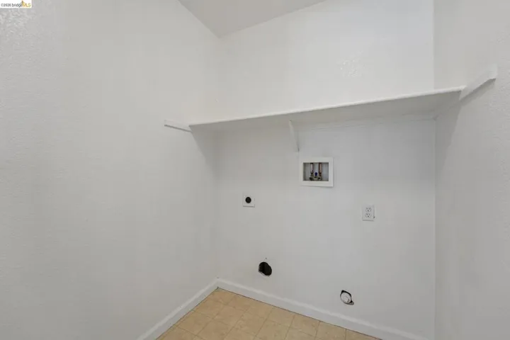 Utility space featuring a built-in white shelf, standard electrical outlet, and utility hookups