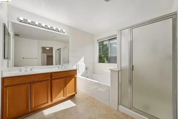 Bathroom featuring a dual-sink wood-finish vanity with a large mirror and overhead lighting