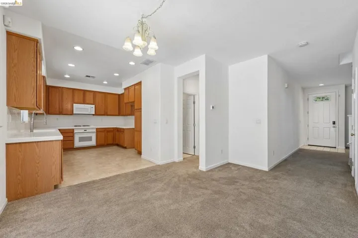 Kitchen featuring wood cabinetry, white appliances, recessed lighting, and a chandelier